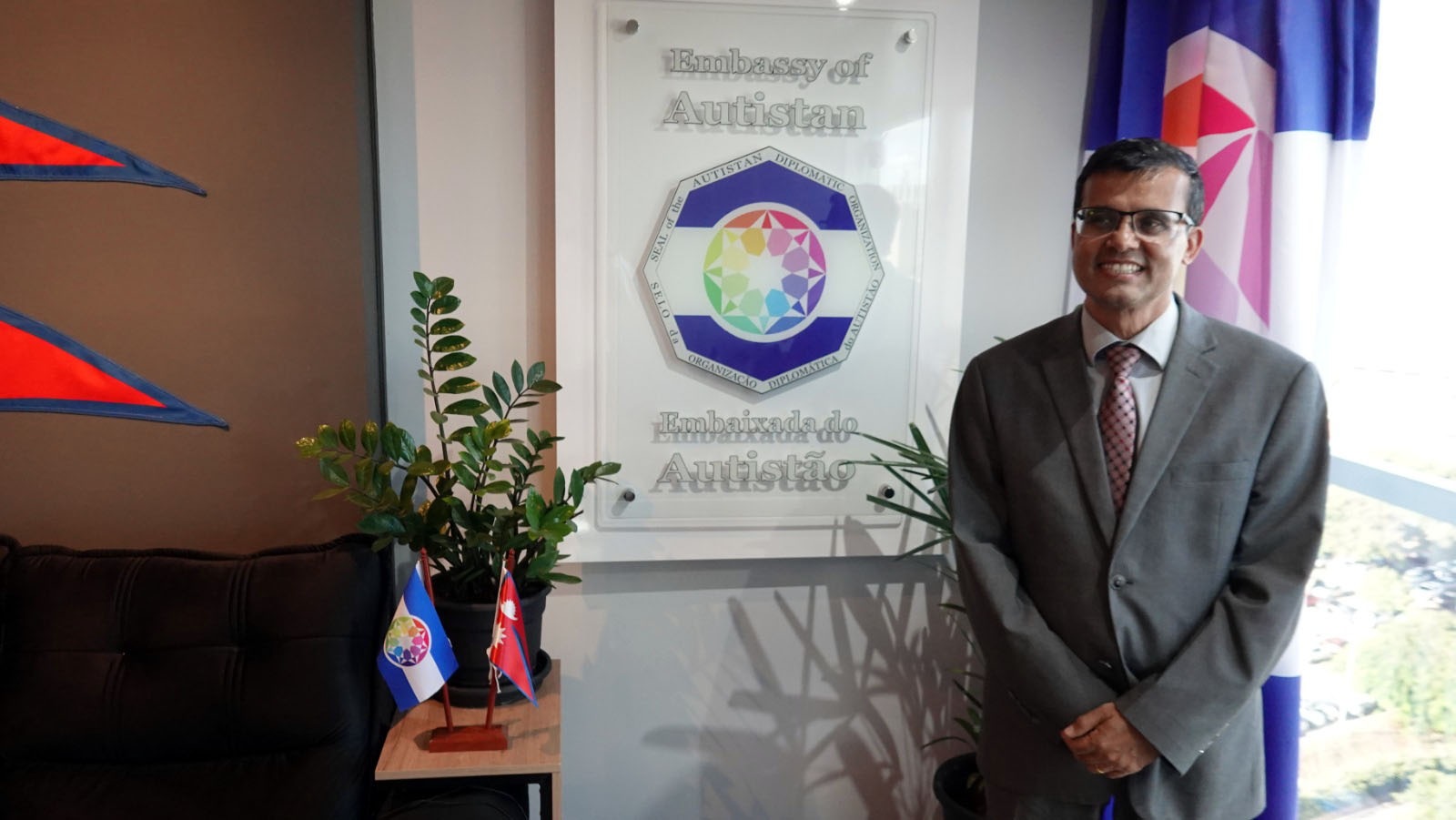 Près de la plaque de l’Ambassade d’Autistan, avec les symboles du Népal et de l’Autistan.