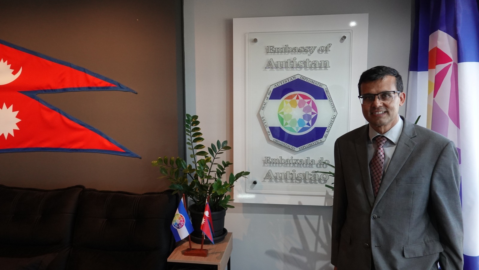 Près de la plaque de l’Ambassade d’Autistan, avec les symboles du Népal et de l’Autistan.